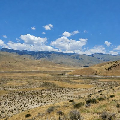 Golden Hills and Mountains Under Blue Sky
