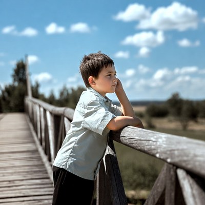 Boy leaning on wooden bridge railing