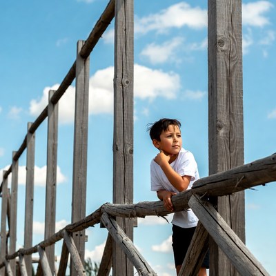Boy leaning on wooden fence