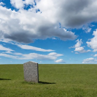 Gravestone in green field under cloudy sky
