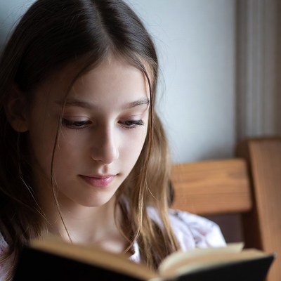 Girl reading book by window