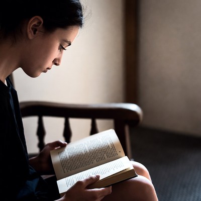 Young woman reading book in chair