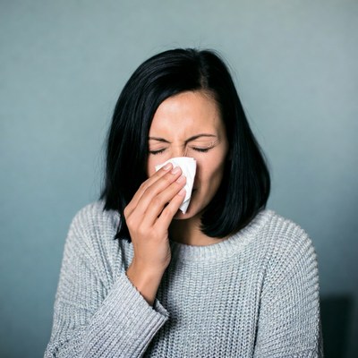 Woman blowing nose with tissue