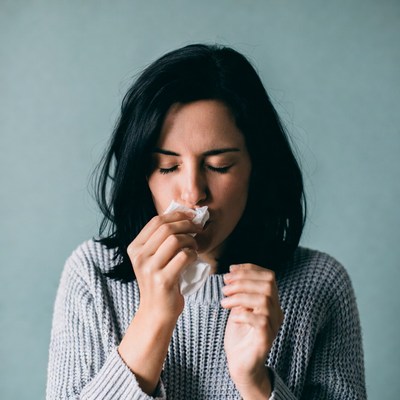 Woman blowing nose with tissue