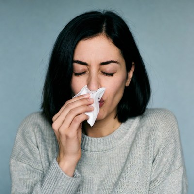 Woman blowing nose with tissue
