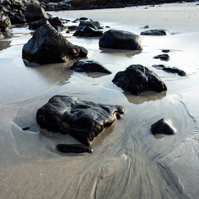 Black rocks on sandy beach