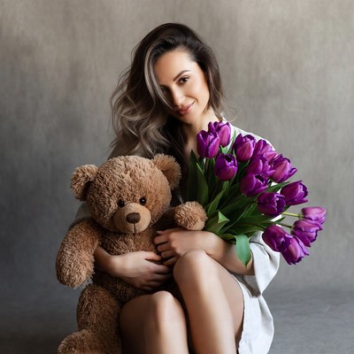Woman holding teddy bear and purple tulips