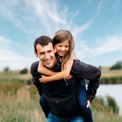 Father carrying daughter on shoulders outdoors