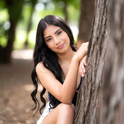 Young Latina woman leaning on tree