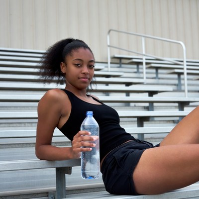 African-American girl holding water bottle on bleachers