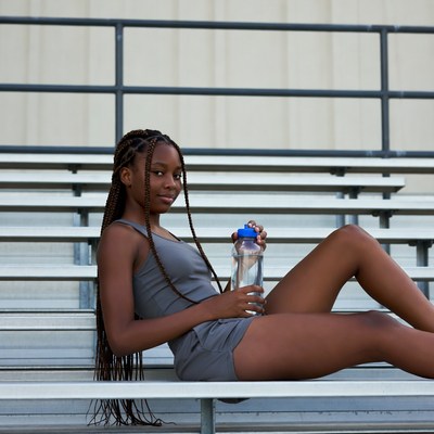 African-American girl with water bottle on bleachers