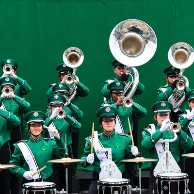 Green-uniformed marching band playing instruments