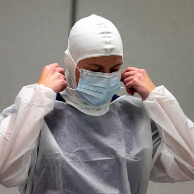 Woman adjusting surgical mask and hood