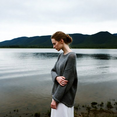 Woman in gray sweater by mountain lake