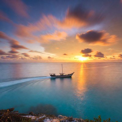 Sailing boat at sunset over turquoise sea
