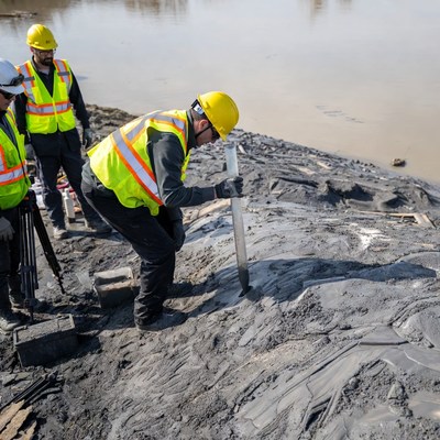 Workers testing soil near riverbank