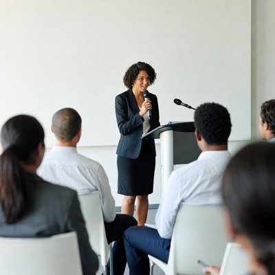 Woman speaking at podium with audience