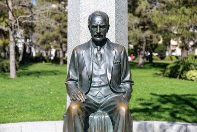Bronze statue of man in suit sitting