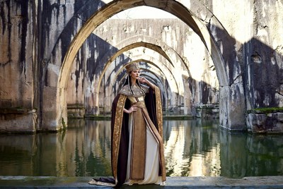 Woman in gold gown at ancient arches
