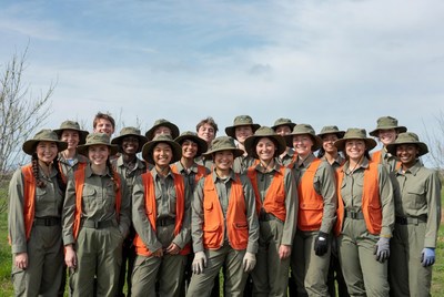 Group of diverse volunteers in orange vests outdoors