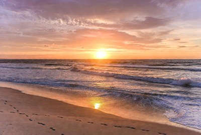 Sunset over beach with footprints
