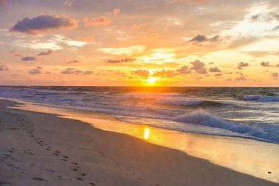 Sunset over beach with footprints