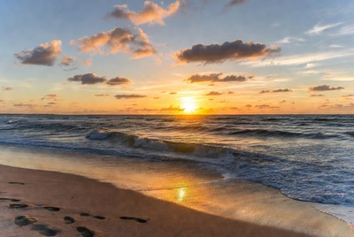 Sunset over beach with footprints