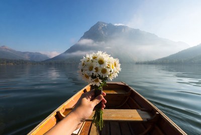 Woman holding daisies in rowboat