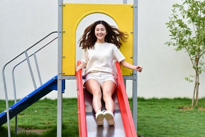 Asian woman sliding down playground slide