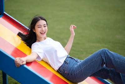 Asian woman sliding on playground slide