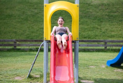 Girl sliding down red playground slide