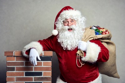Santa Claus with sack of gifts by chimney