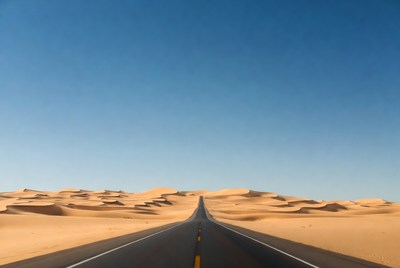 Straight road through desert dunes