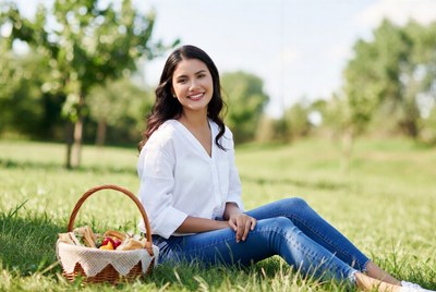 Smiling woman with picnic basket in grass