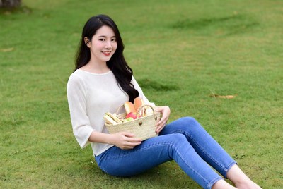 Asian woman holding fruit basket on grass