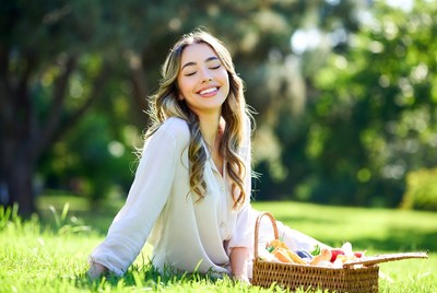 Smiling woman with picnic basket on grass