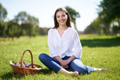 Smiling woman with picnic basket on grass