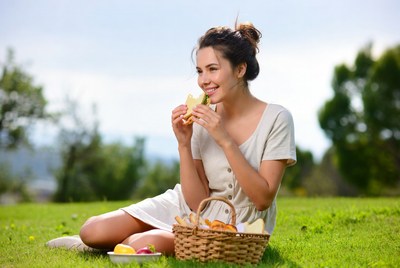 Woman eating sandwich picnic outdoors