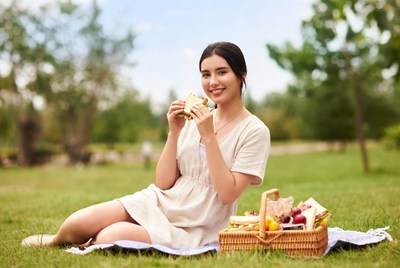 Asian woman eating sandwich picnic