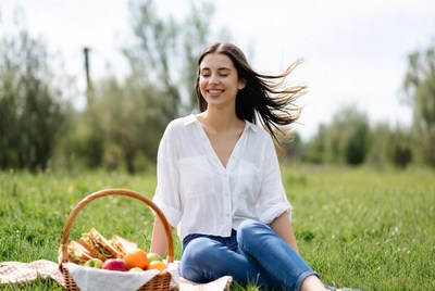 Smiling woman with picnic basket in grass