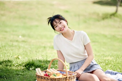 Asian woman with picnic basket in grass