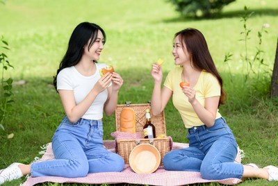 Two Asian women eating picnic outdoors