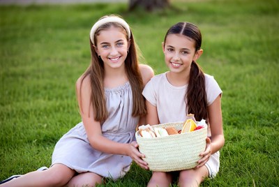 Two girls holding picnic basket on grass