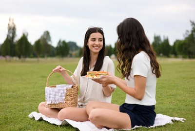 Two women sharing sandwiches at picnic