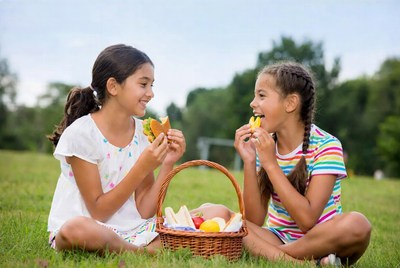 Two girls eating sandwiches in park