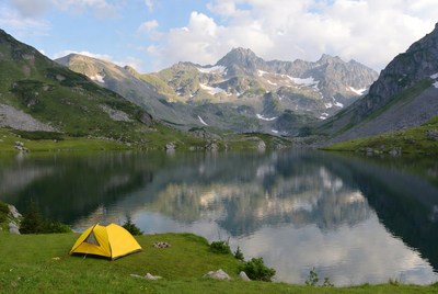 Yellow tent by alpine lake mountains