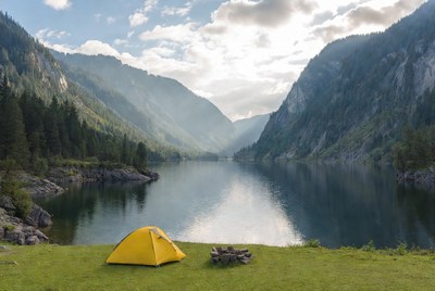 Yellow tent by lake in mountains