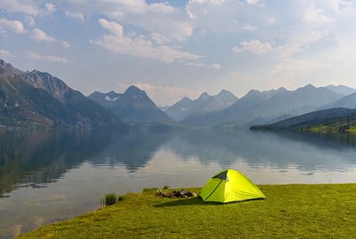 Green tent by lake with mountains