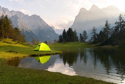 Green tent by mountain lake