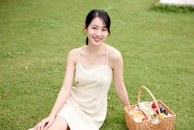 Asian woman holding picnic basket on grass